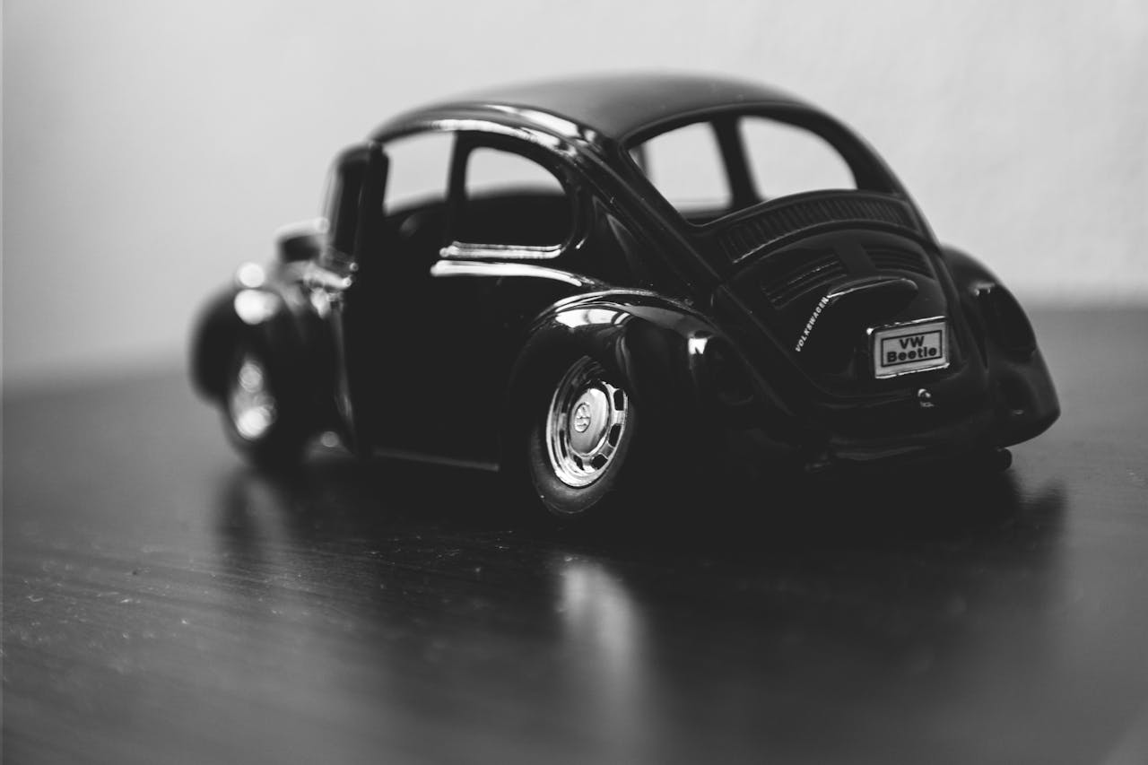 services-05 Black and white macro of a classic VW Beetle toy car model on a table.